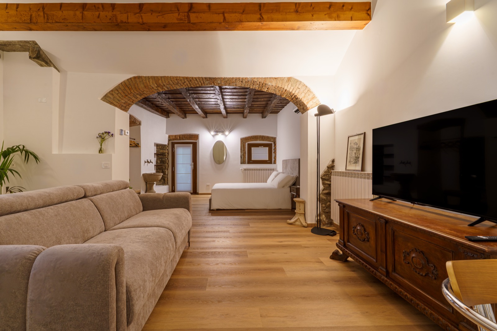 Open-plan living space with wooden beams and a brick arch – Bergamo DiMora, Bergamo